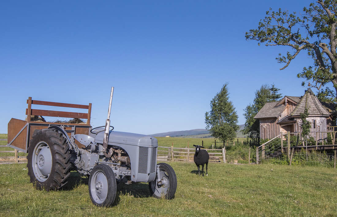 Tractor in field by glamping treehouse